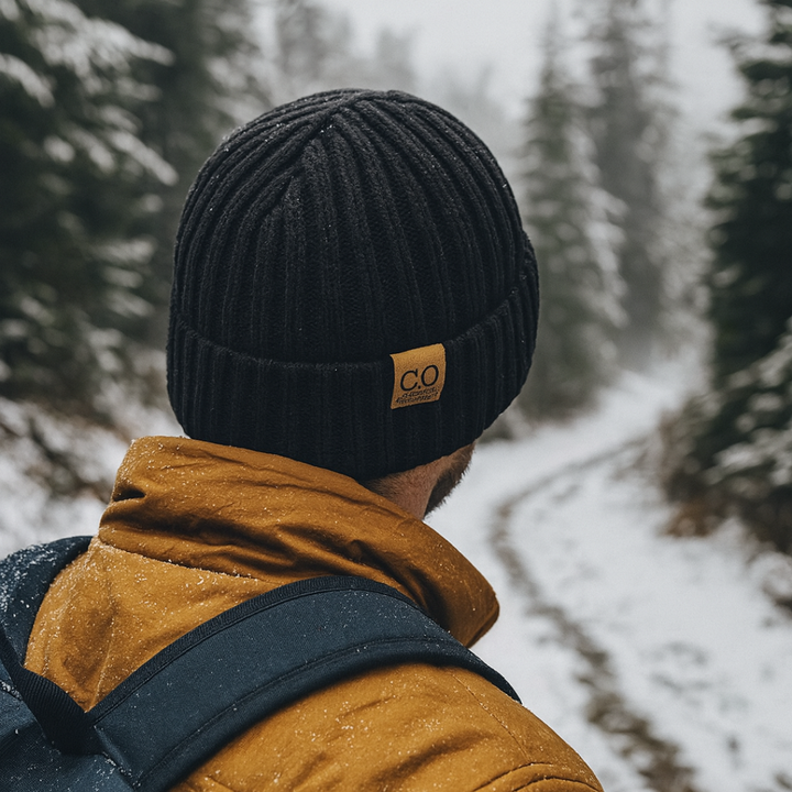 Man wearing the fleece lined winter hat in Black on a snowy trail
