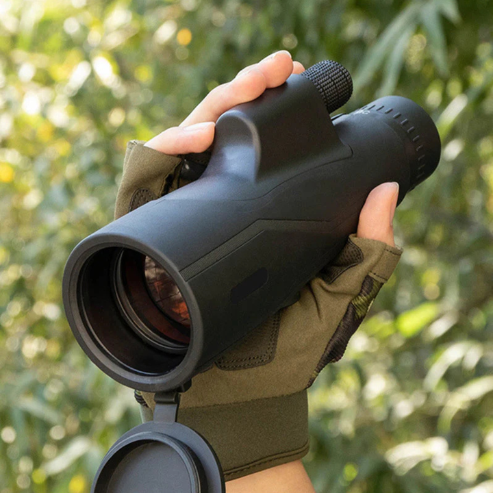 Hand in a glove holding the compact monocular outdoors