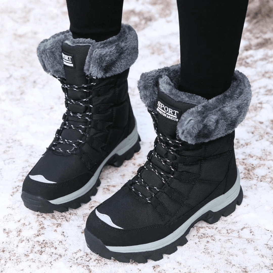 Women's snow boots in Black with gray faux fur cuff, worn in the snow