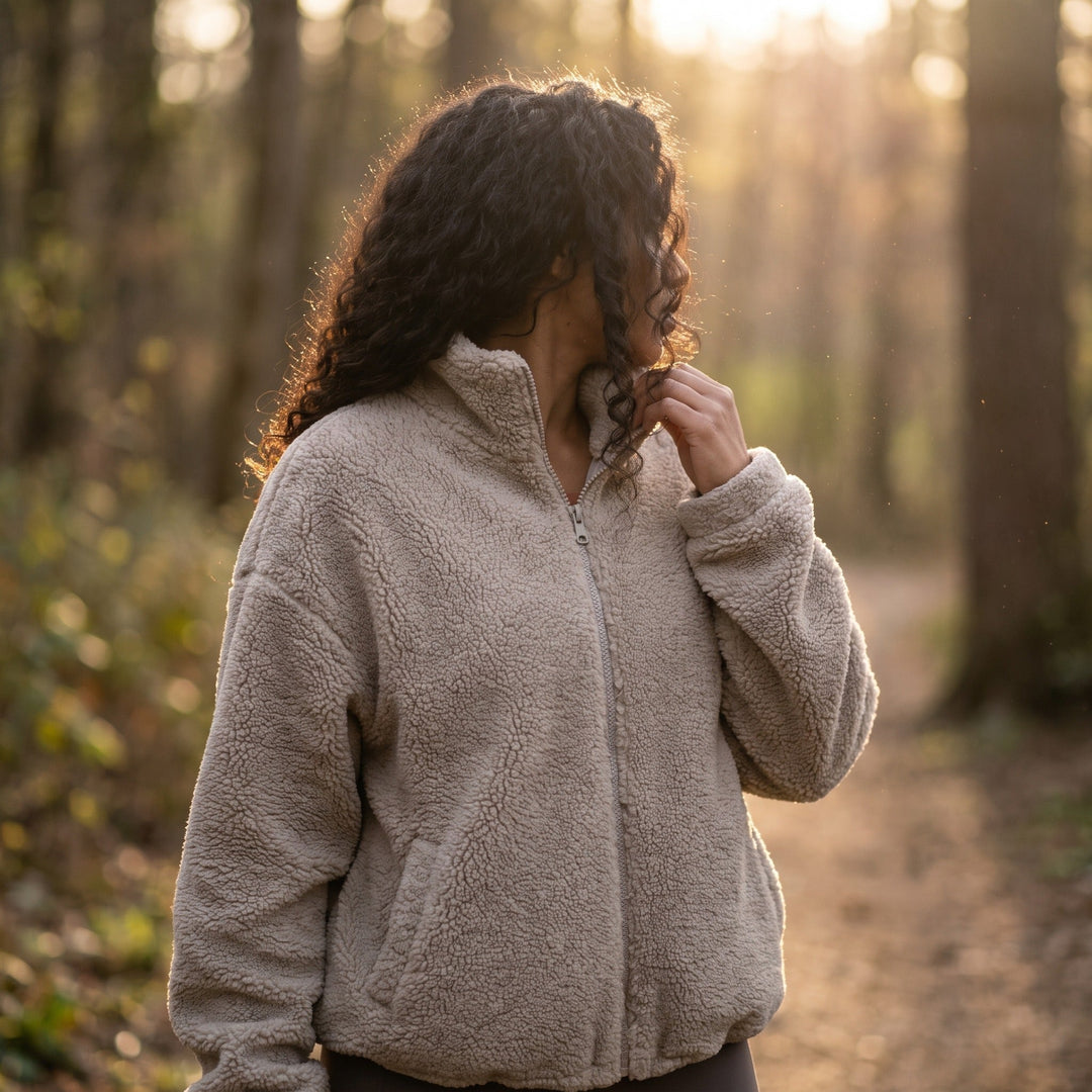 Woman wearing a sherpa fleece jacket with high collar on a forest trail