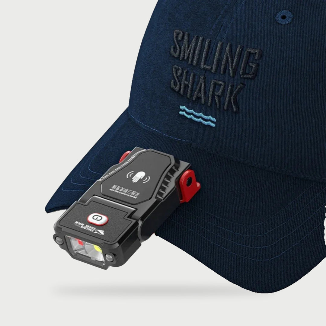 Clip on LED cap light with motion sensor clipped to the brim of a navy cap