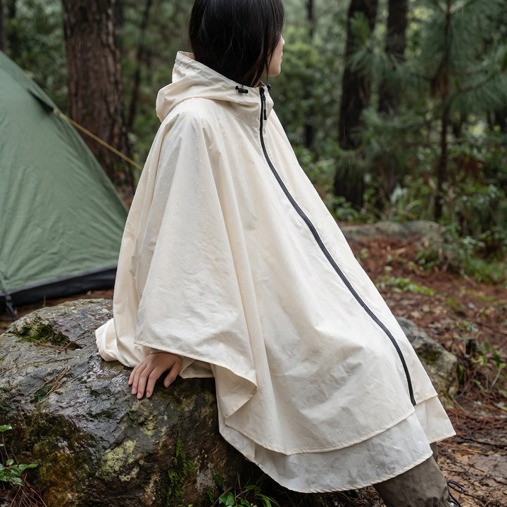Woman wearing the hooded rain poncho in Off White at a forest campsite