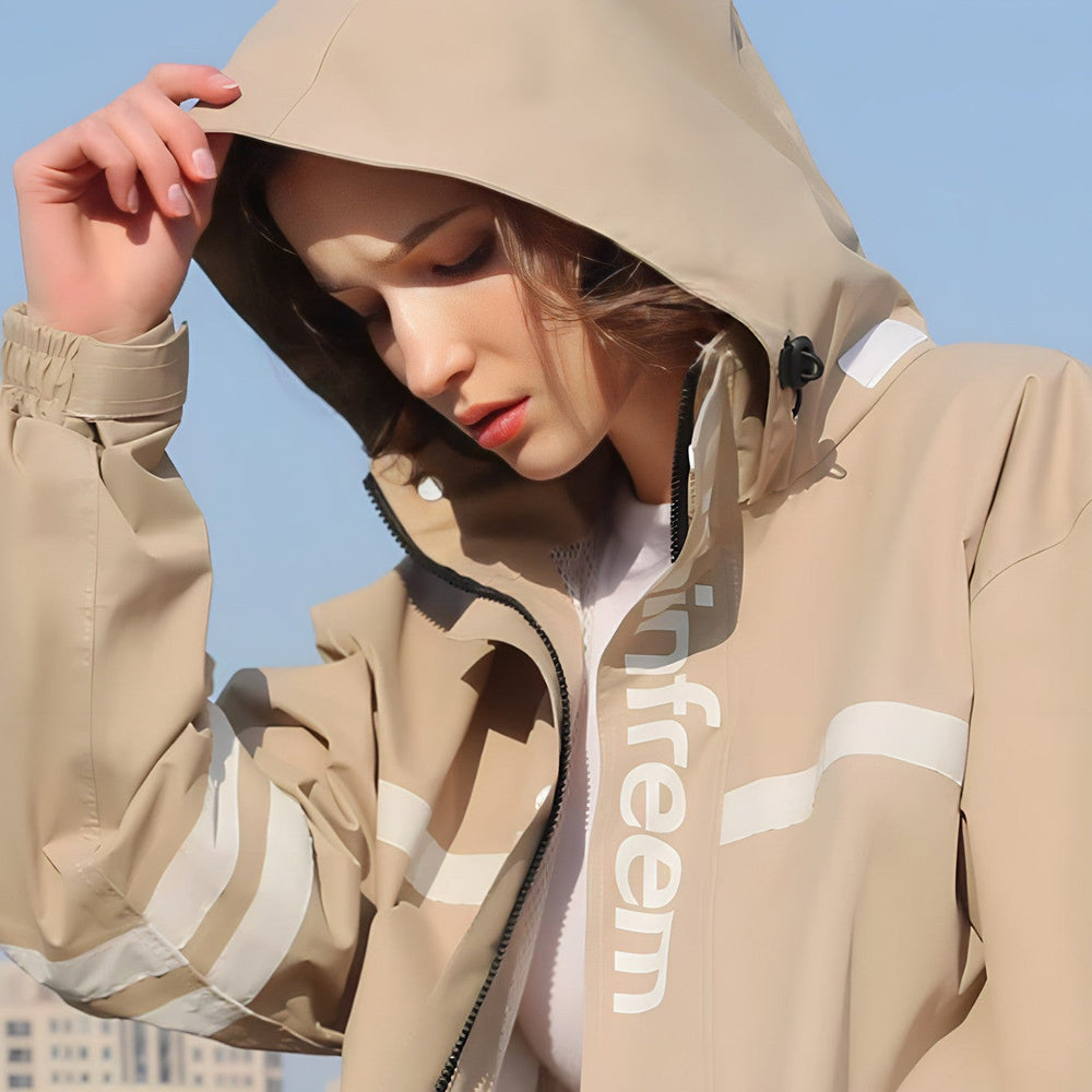 Woman pulling up the drawstring hood of the rain suit jacket in Taupe