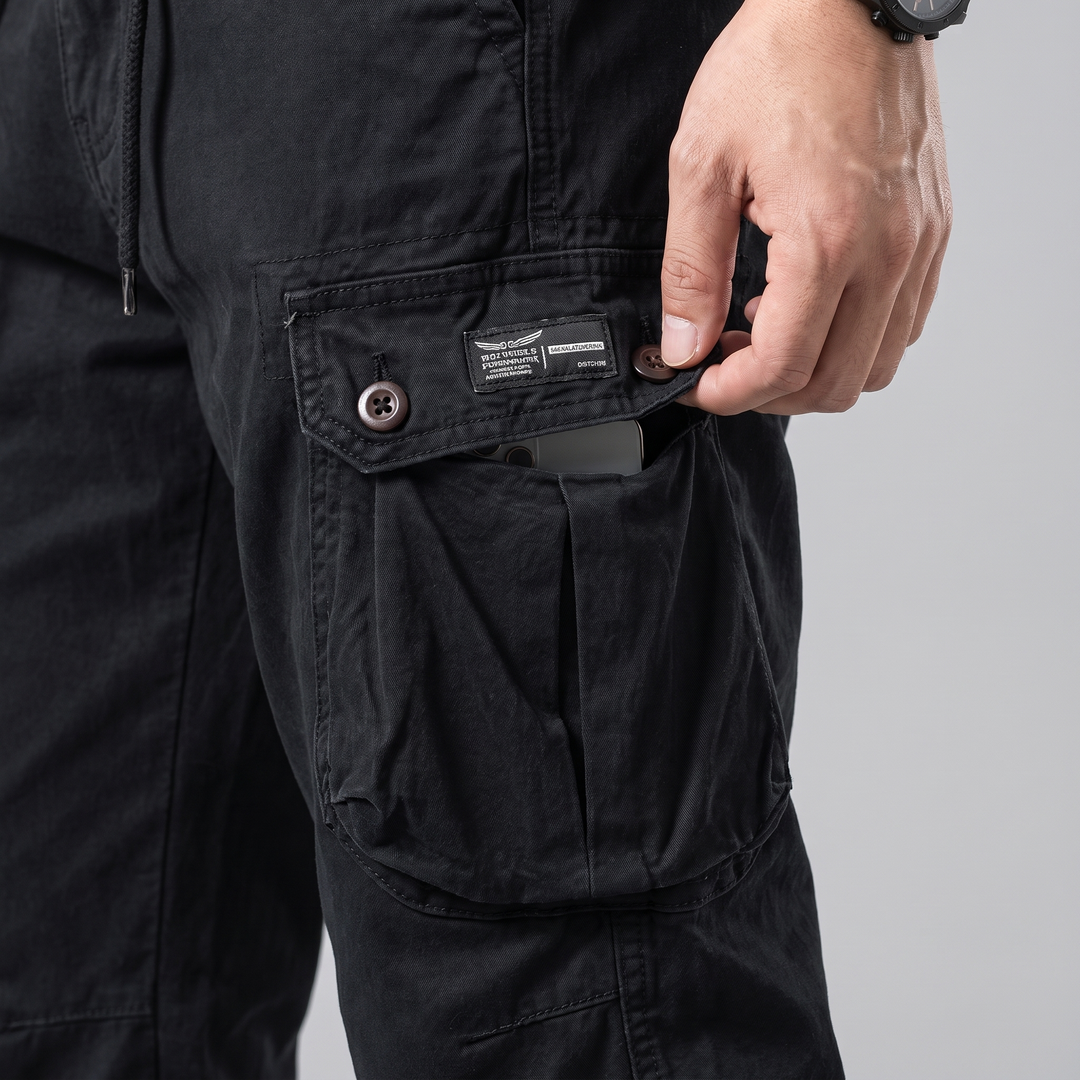 Close-up of the button flap thigh cargo pocket on black cargo pants with a phone inside