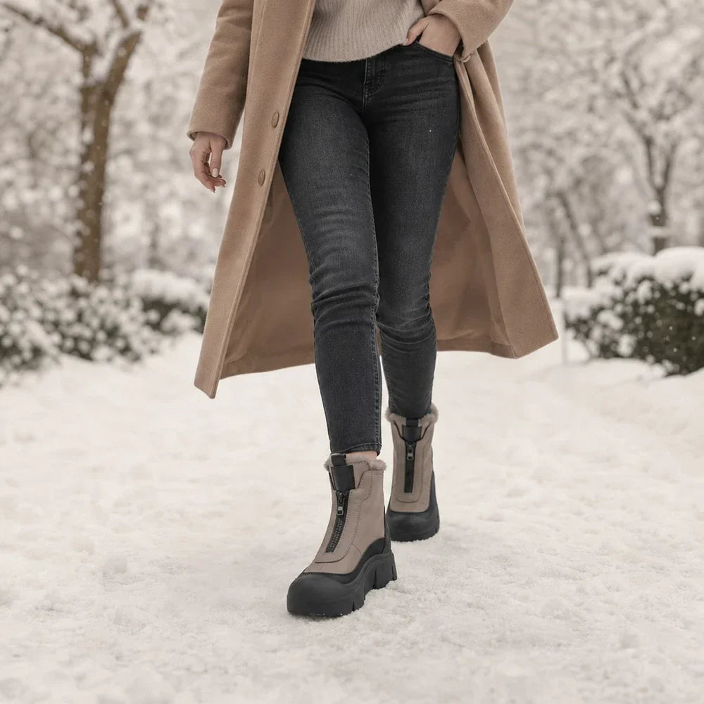 Woman walking through snow in taupe front zip snow boots