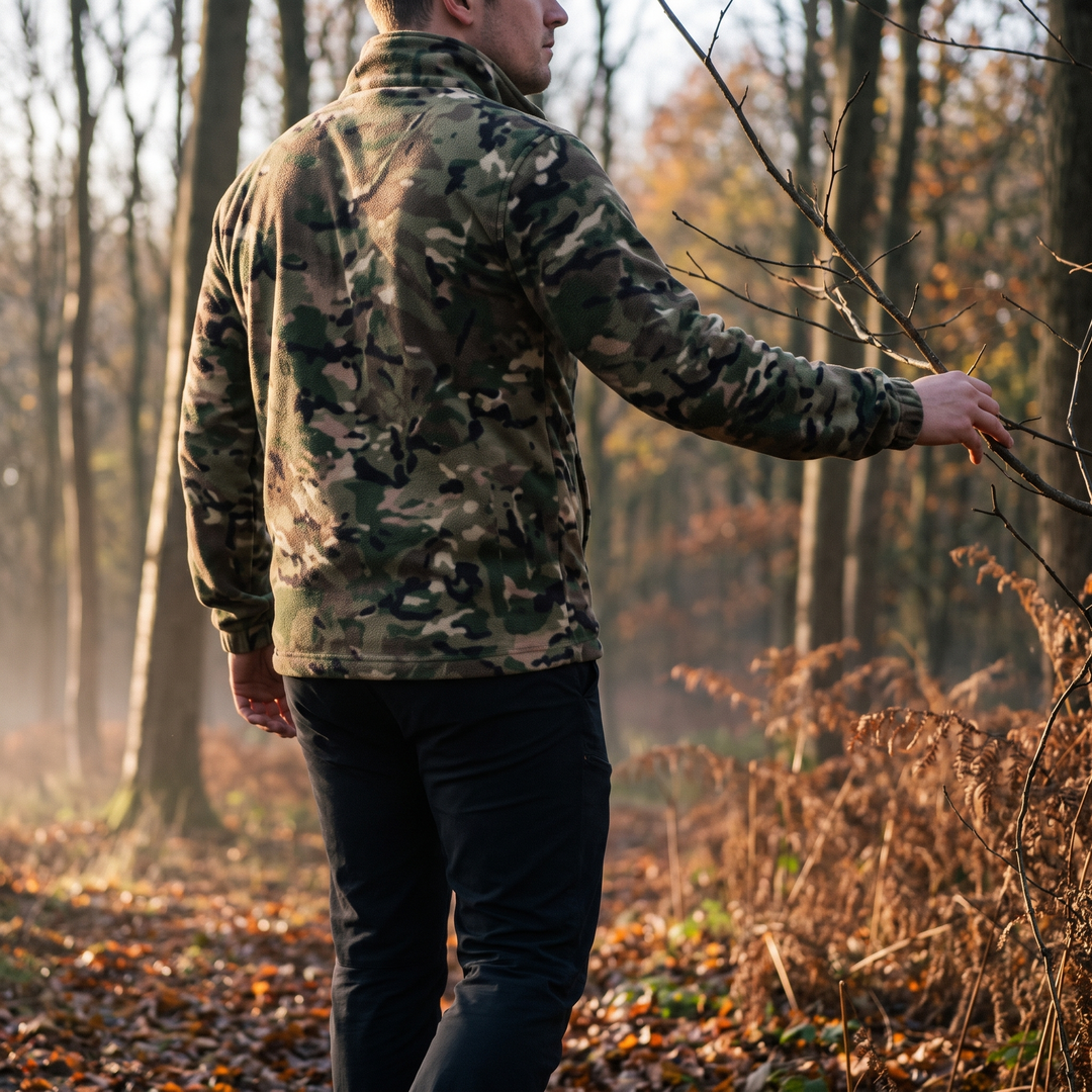 Man in camo fleece jacket moving quietly through autumn woodland at first light