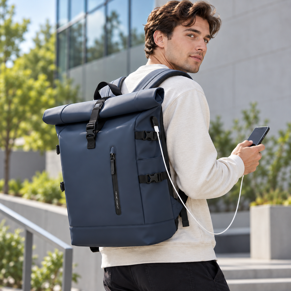 Man carrying the roll top backpack in Navy and charging his phone through the USB port