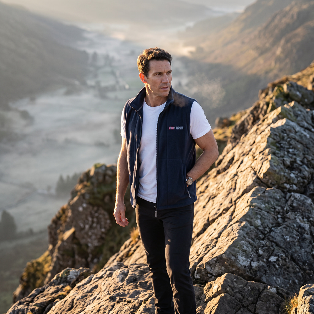 Man wearing the navy fleece vest on a rocky ridge at first light