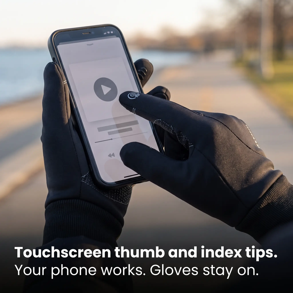 Gloved index fingertip tapping a phone screen on a lakefront path, touchscreen thumb and index tips
