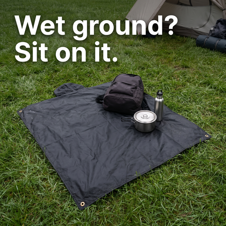 The poncho laid flat on wet grass as a ground sheet