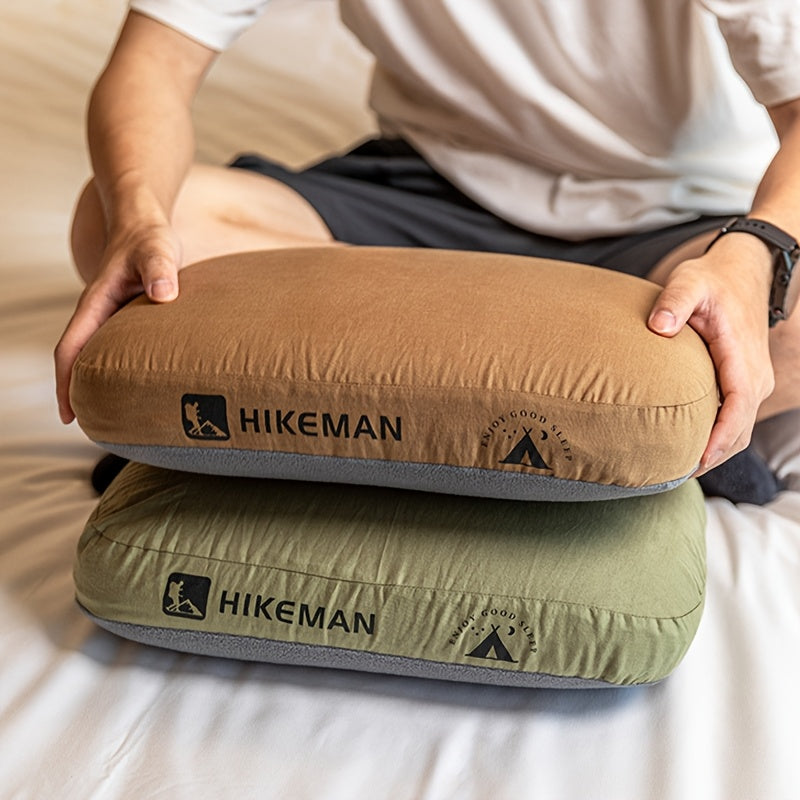 Two memory foam camping pillows, one brown and one green, stacked on a bed