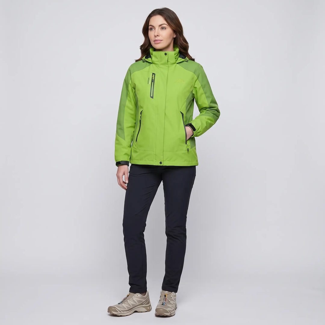Full-length view of a woman in the green insulated rain jacket with dark pants and trail shoes
