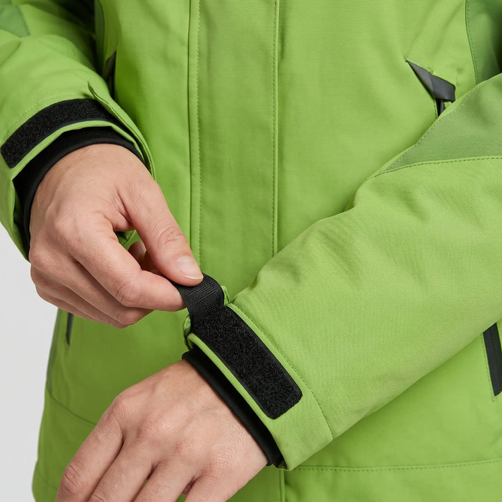 Hand closing the hook-and-loop cuff tab on the green insulated rain jacket