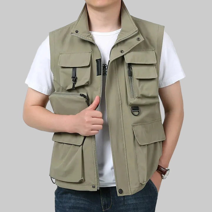 Person wearing a beige vest with multiple pockets on a white background