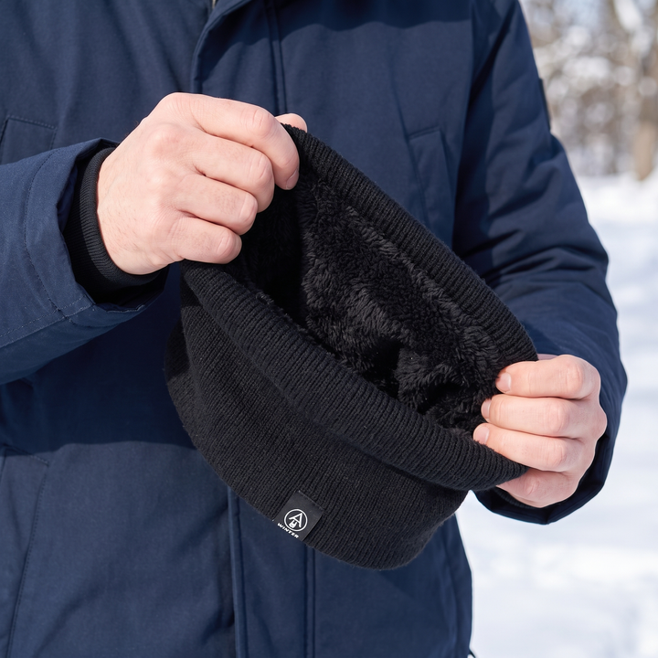 Hands peeling back the rim of the black neck gaiter revealing the plush fleece interior