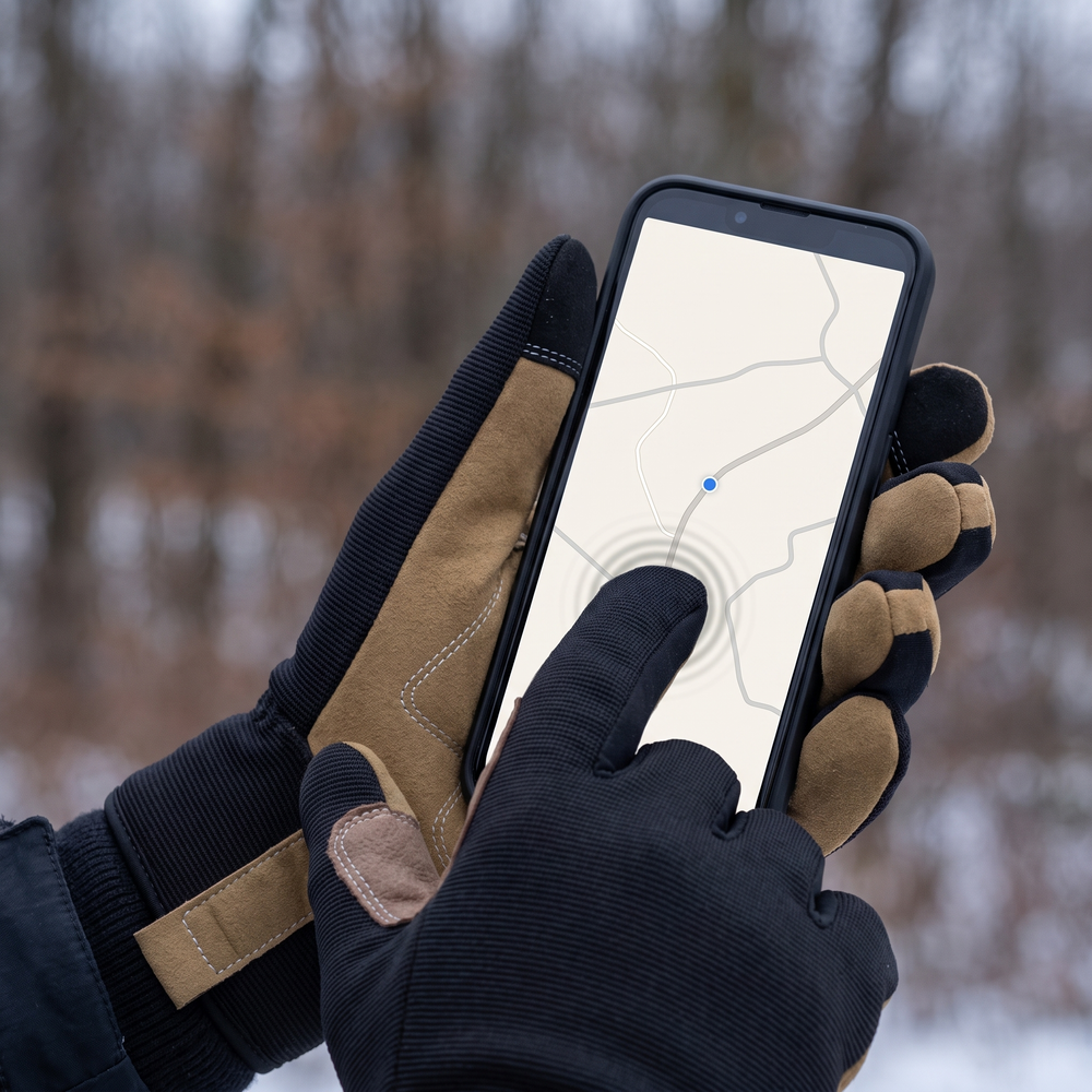 A gloved thumb working a phone screen without removing the glove